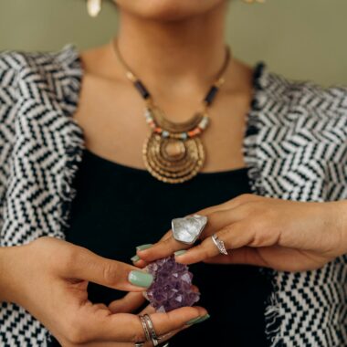 A woman with stylish jewelry holds an amethyst, perfect for fashion and crystal enthusiasts.