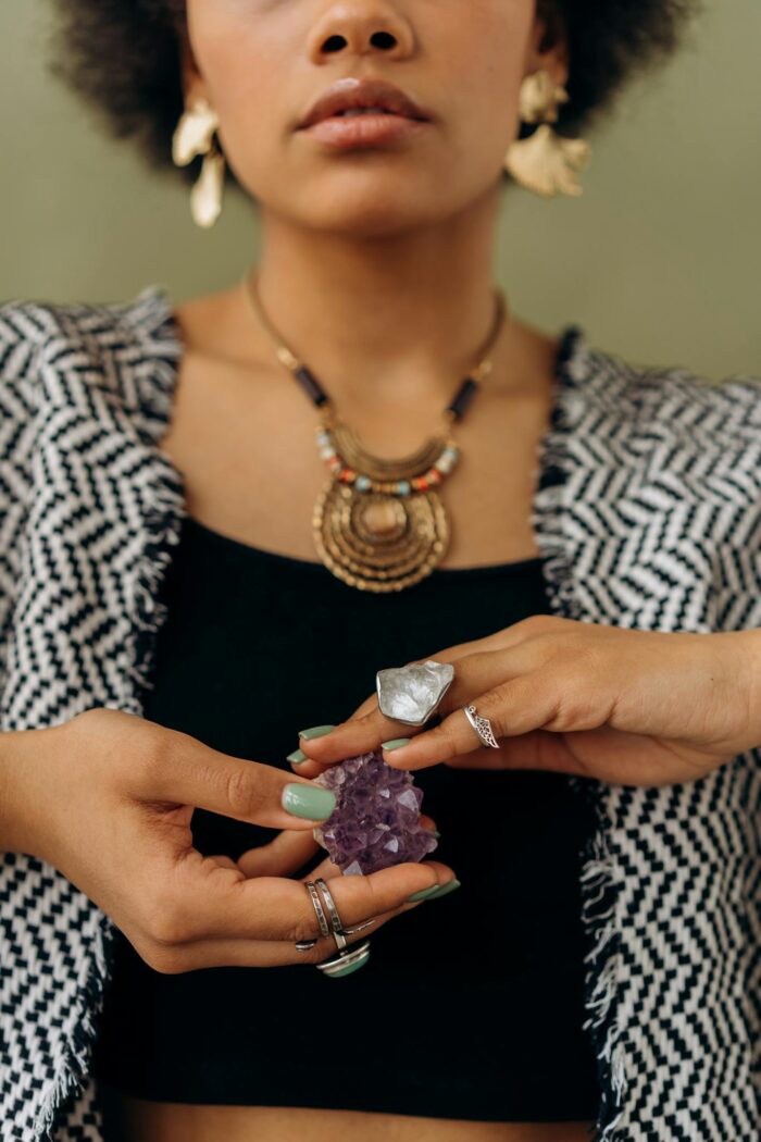 A woman with stylish jewelry holds an amethyst, perfect for fashion and crystal enthusiasts.