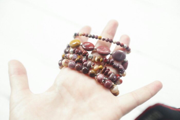 Close-up of a hand holding colorful beaded bracelets against a white background, showcasing vibrant jewelry.