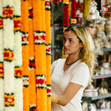 Woman choosing colorful traditional garlands in a vibrant Indian craft market.