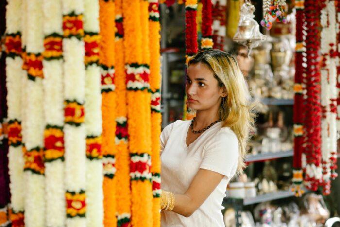 Woman choosing colorful traditional garlands in a vibrant Indian craft market.